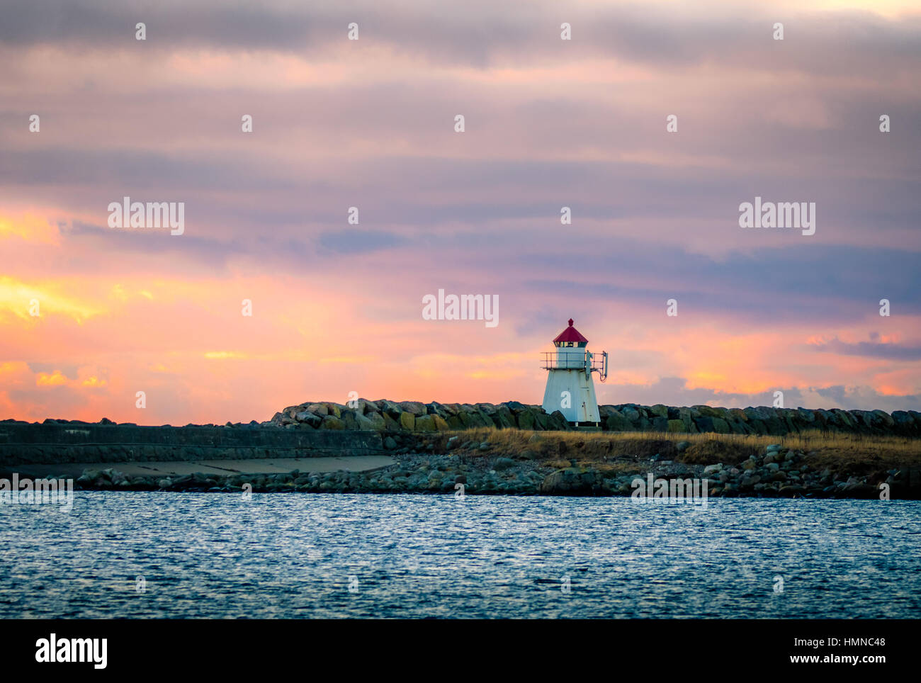 A small lighthouse at Lista in Southern Norway in evening light with beautiful blue and pink sky and blue ocean in front Stock Photo