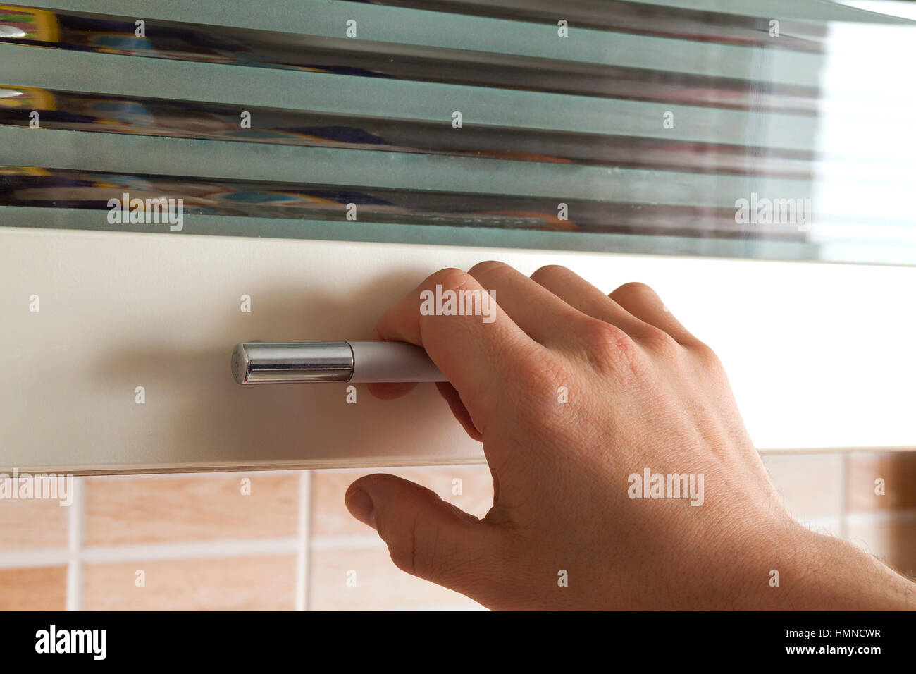 Mans hand open the kitchen cupboard doors, close up Stock Photo