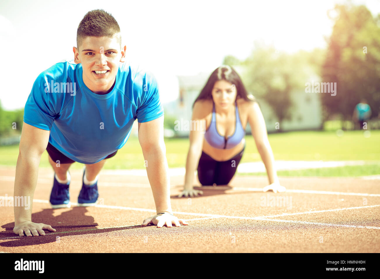 Young adult couple doing together push ups exercise outdoor on running ...