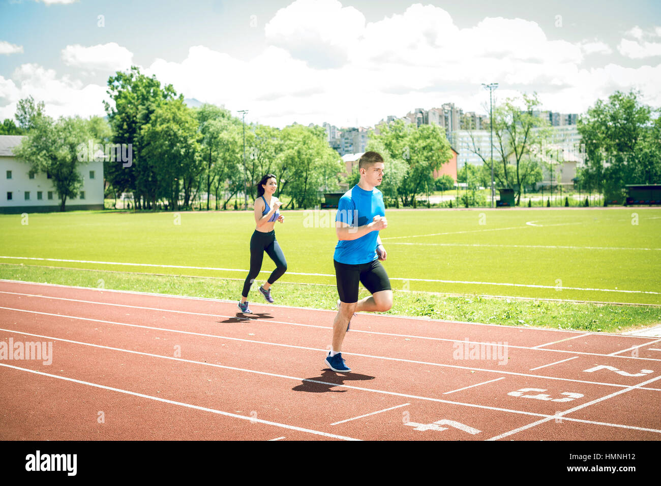 Fitness running couple jogging on athletics stadium track open air