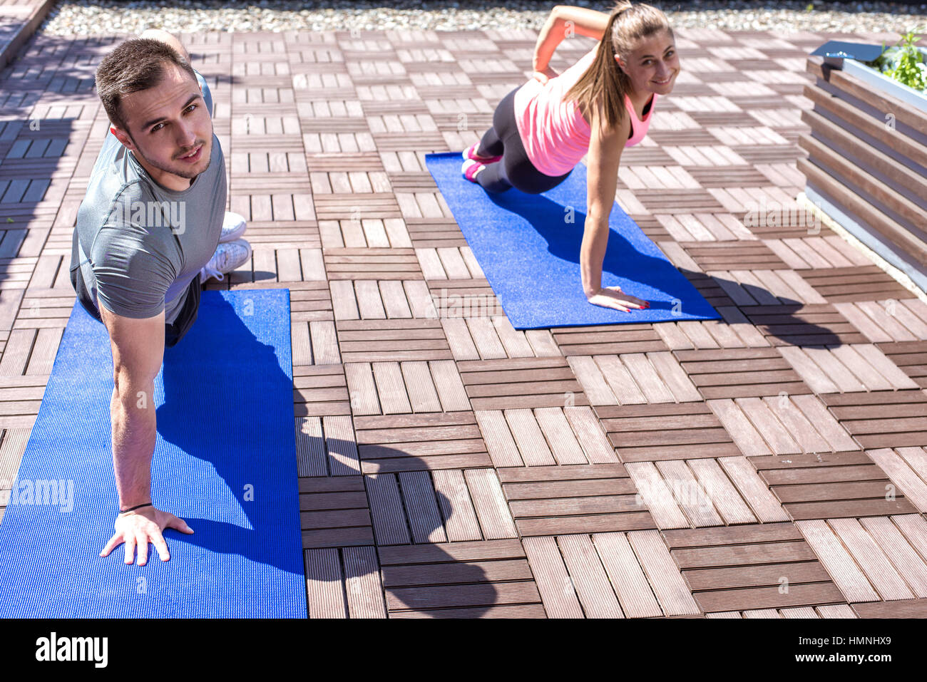 Young couple doing together side plank exercise on the rooftop, outdoors. Stock Photo