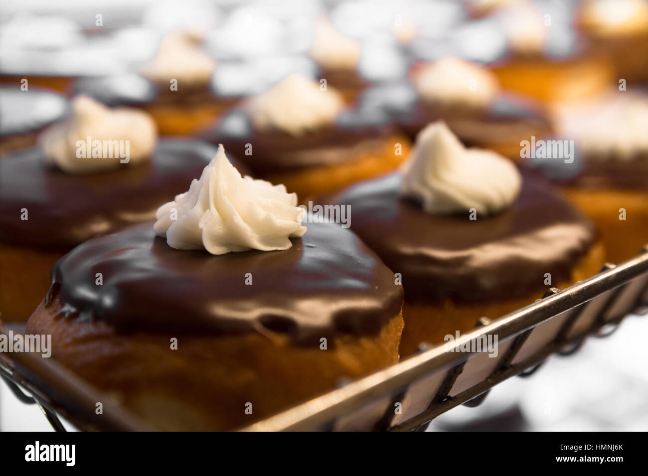 Delicious bakery display of cream filled chocolate frosted donuts Stock