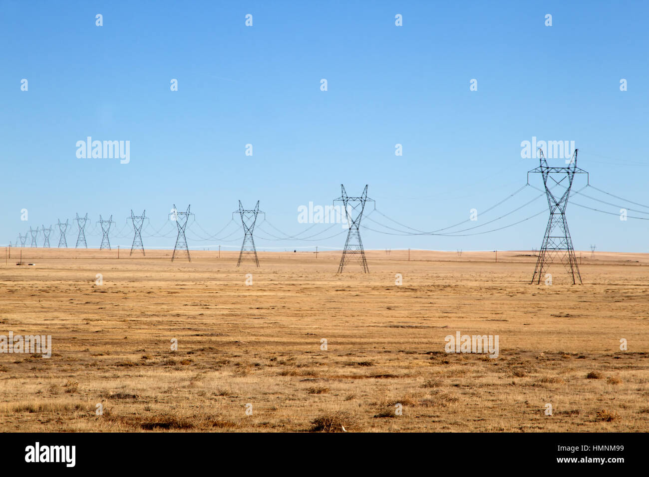 Row of High Voltage Power Lines under a Blue Sky on the plains of