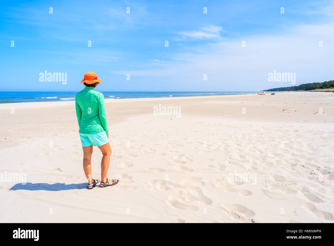 Young woman standing on white sand and looking at beautiful beach, Baltic Sea, Poland Stock Photo