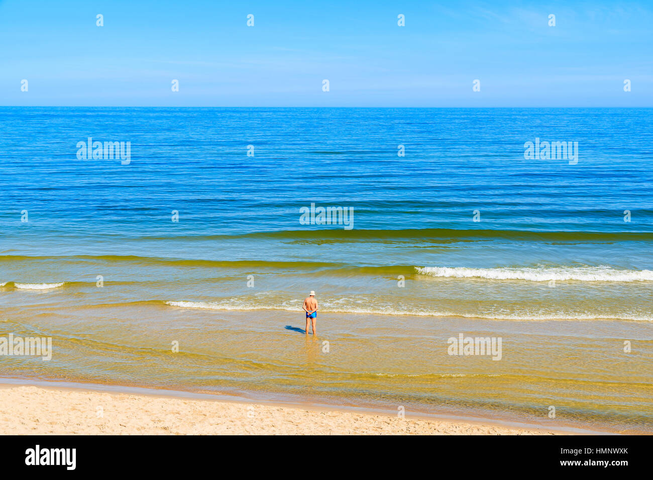 Man standing in water on beach in Jastrzebia Gora, Baltic Sea, Poland Stock Photo