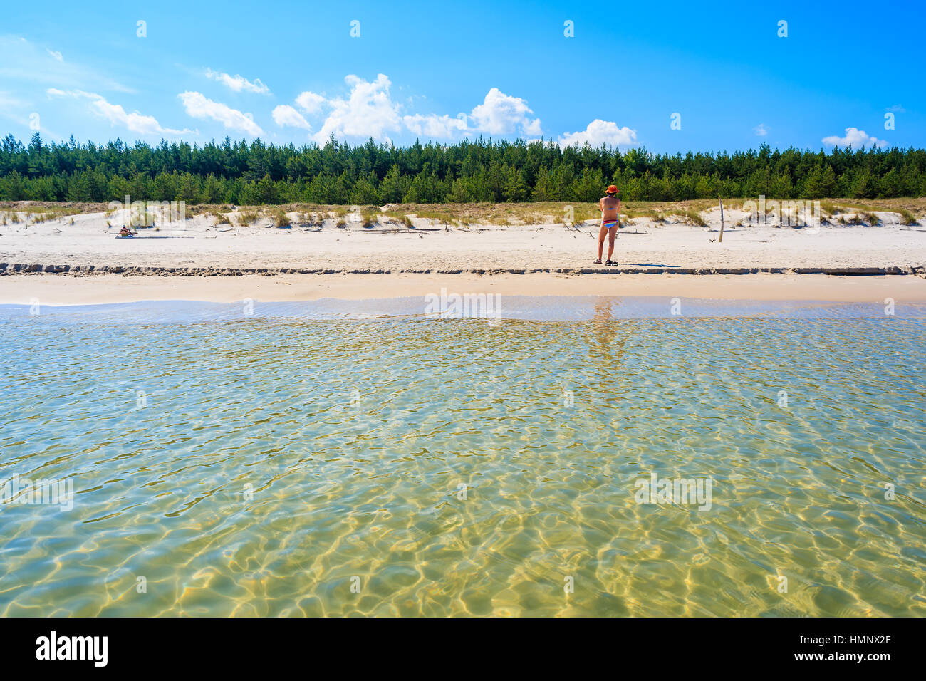 Young woman in swimsuit standing on Bialogora beach with crystal clear water, Baltic Sea, Poland Stock Photo