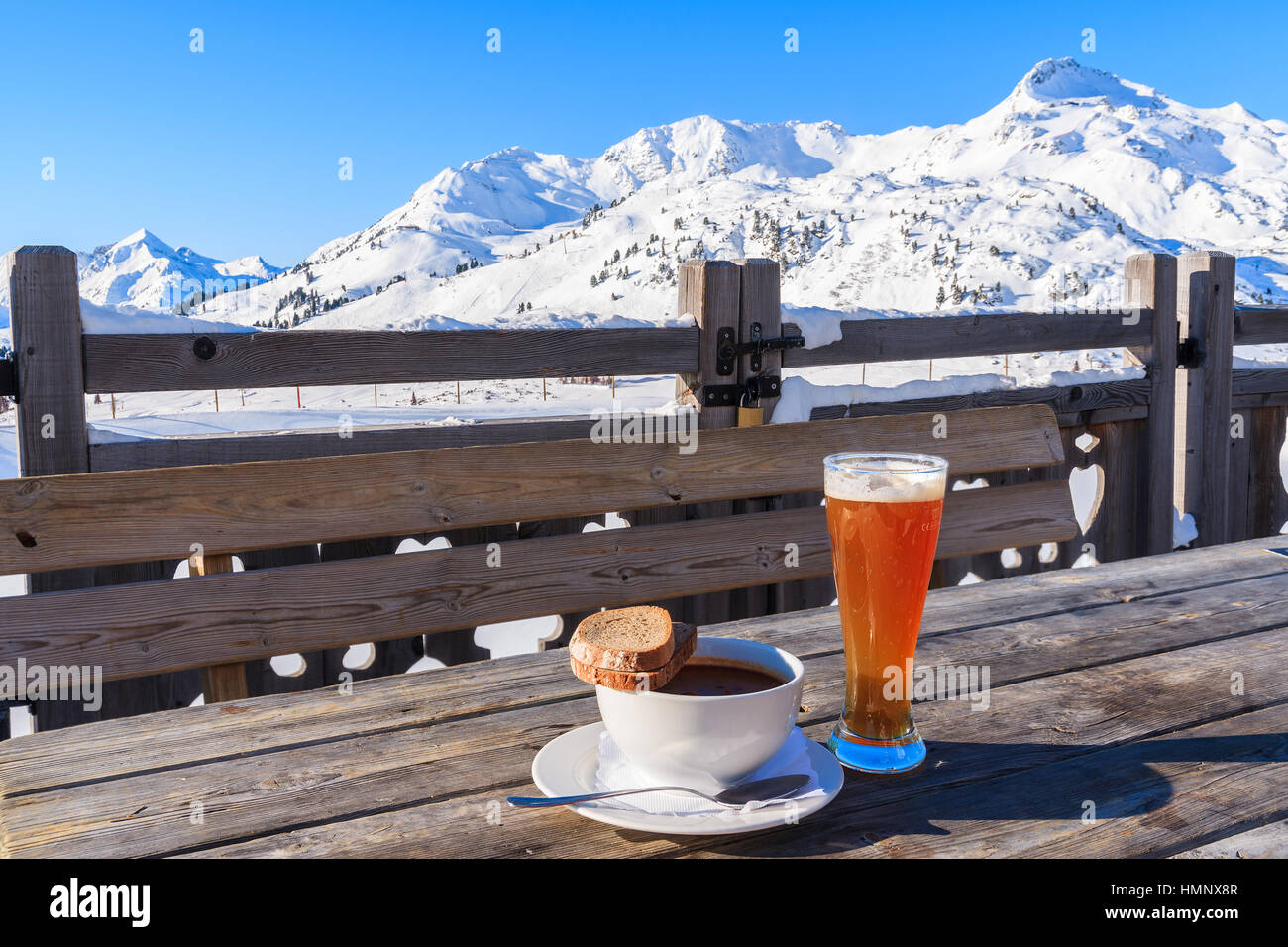 Glass of cold beer and hot soup on wooden table of mountain hut in Obertauern ski area, Austria Stock Photo
