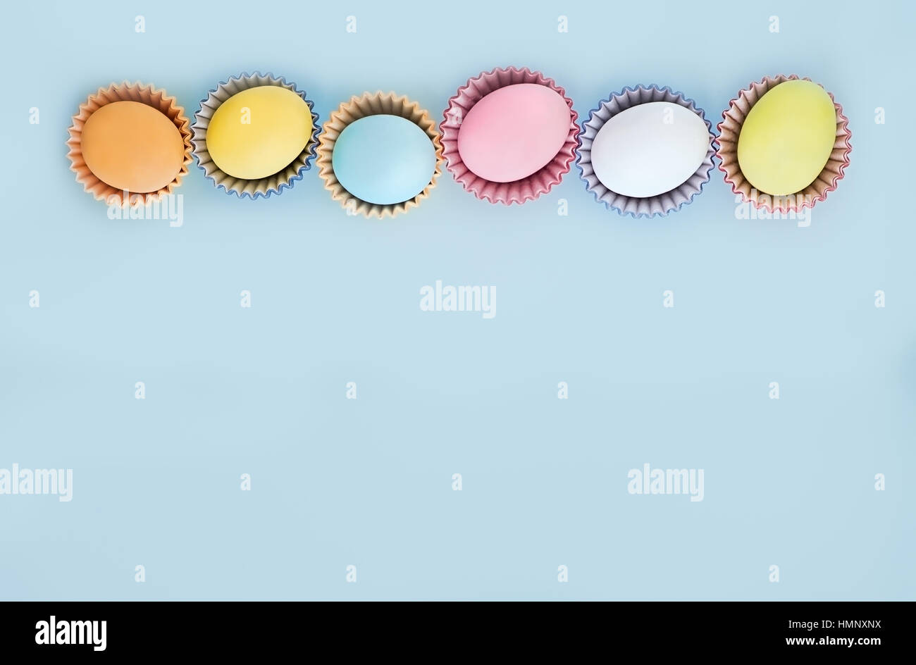 Flat lay row of colorful eggs on a light blue background.  Pastel colors, vintage card. Negative space for text Stock Photo