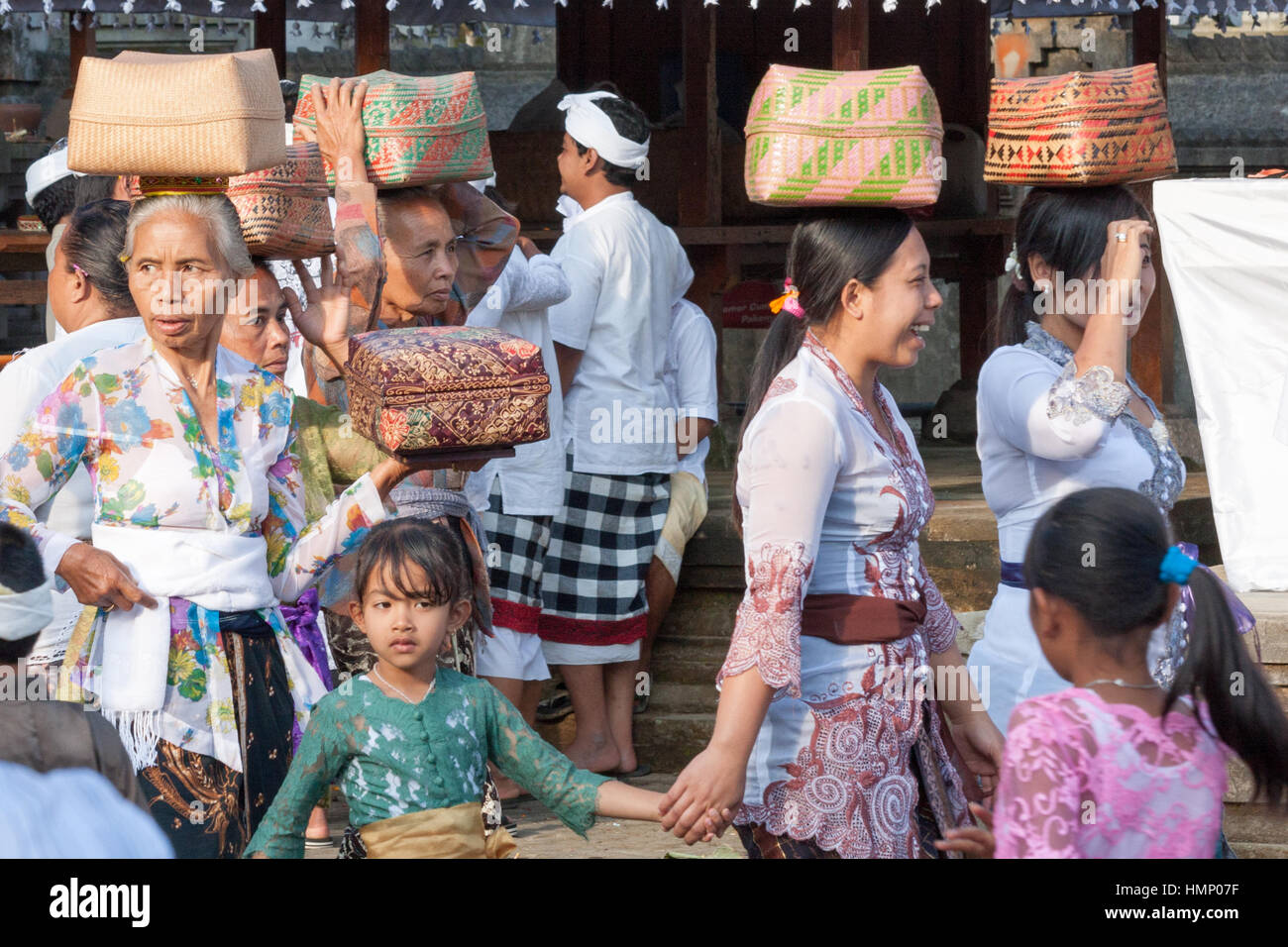 Women with baskets of offerings and children at the temple during the Galungan festival in Bali, Indonesia Stock Photo