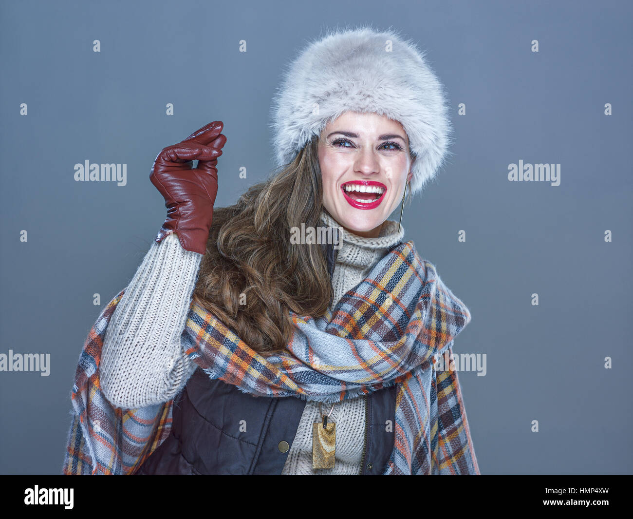 Winter things. Portrait of happy trendy woman in fur hat isolated on cold blue background snapping fingers and looking on copy space Stock Photo