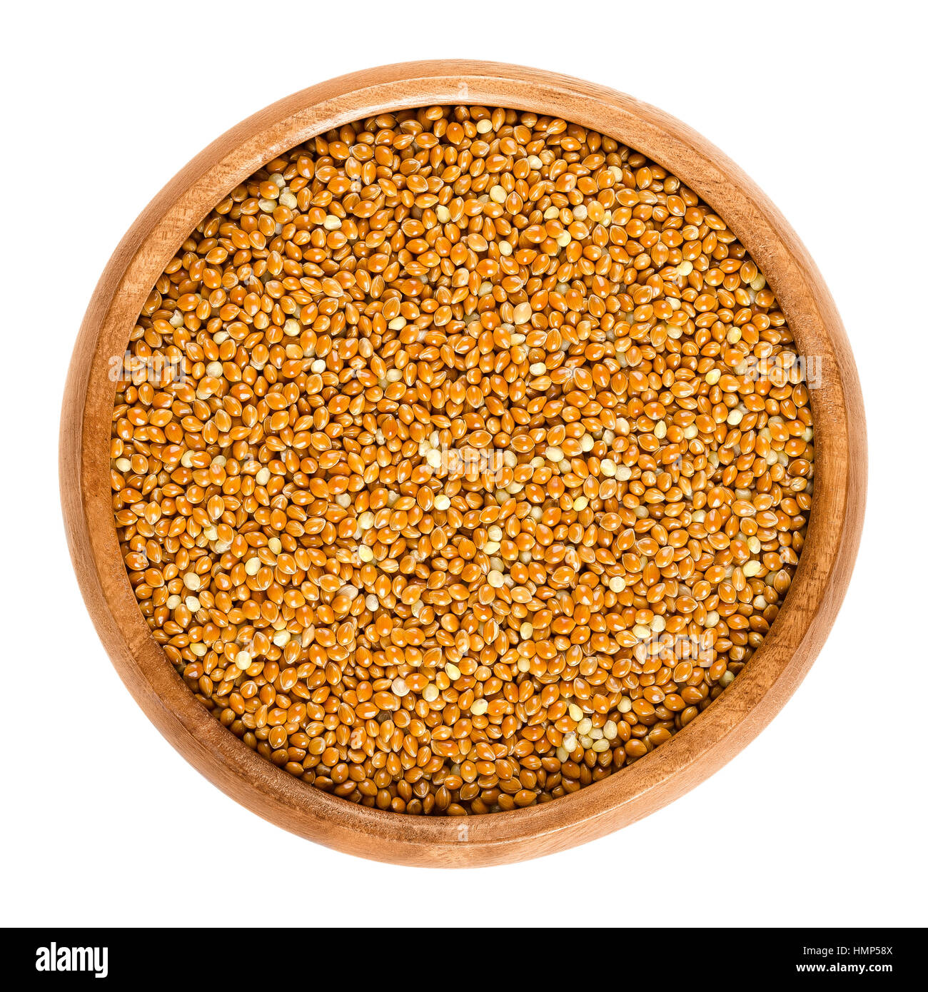 Wholemeal brown millet in a wooden bowl. Reddish colored archetype millet grains. Mineral rich cereal. Edible, raw, wild and organic. Macro photo. Stock Photo