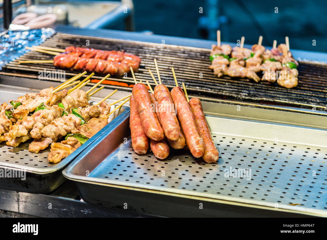 Hot dogs and kebabs on grill at an Asian night market Stock Photo