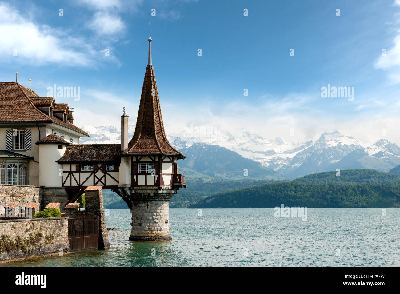 Beautiful little tower of Oberhofen castle in the Thun lake with mountains on background in Switzerland, near Bern. Stock Photo