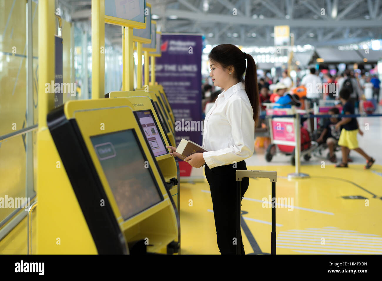 Young Asian businesswoman using self check-in kiosks in airport. Technology in airport. Stock Photo