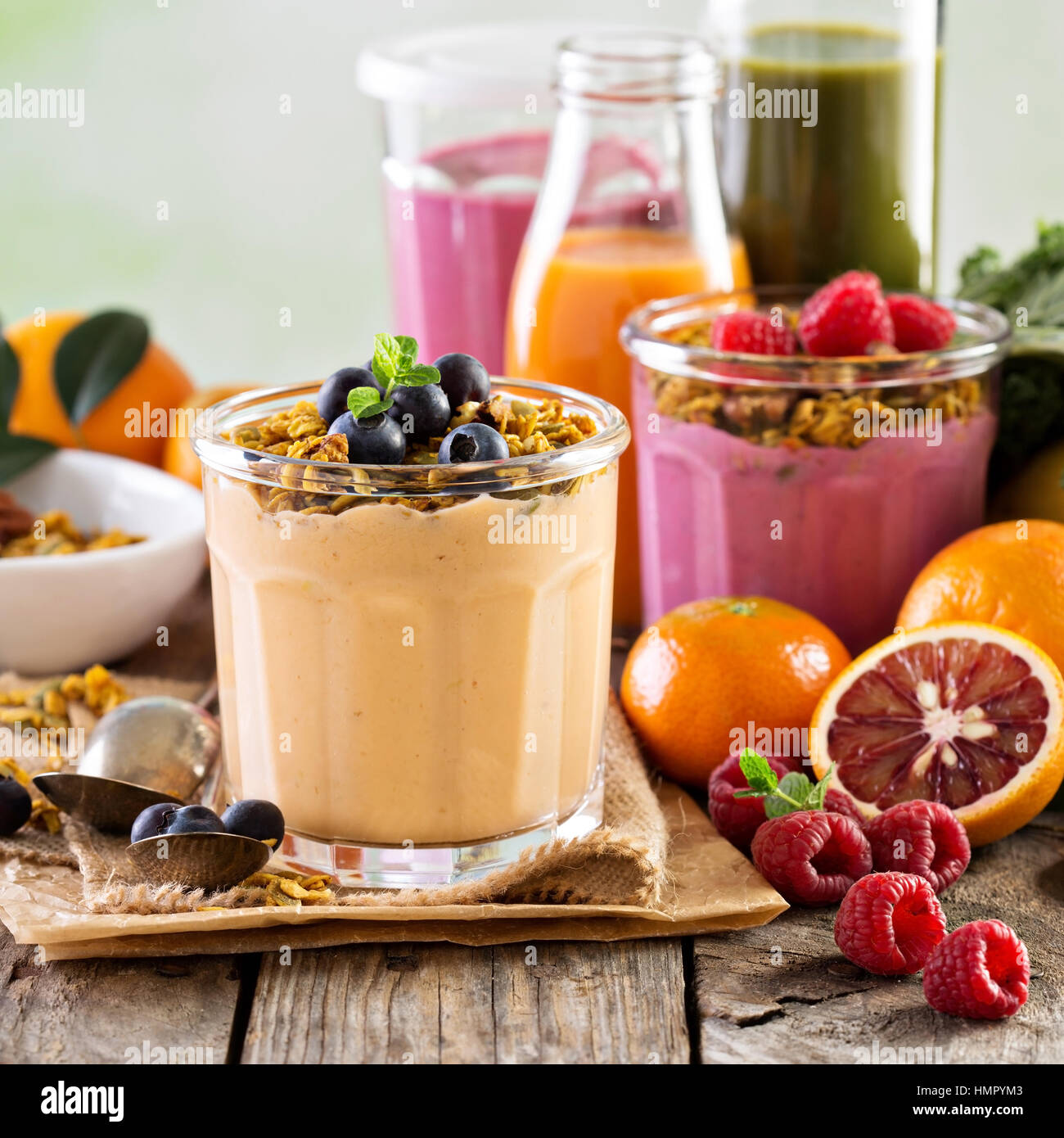 Orange mango smoothie with granola on top and variety of fruits and