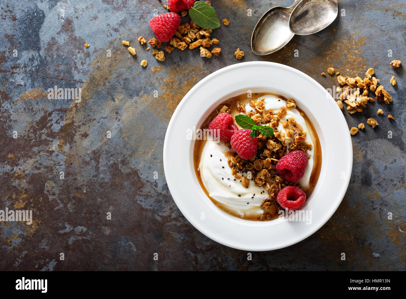 Yogurt bowl with granola, raspberry and maple syrup overhead shot Stock