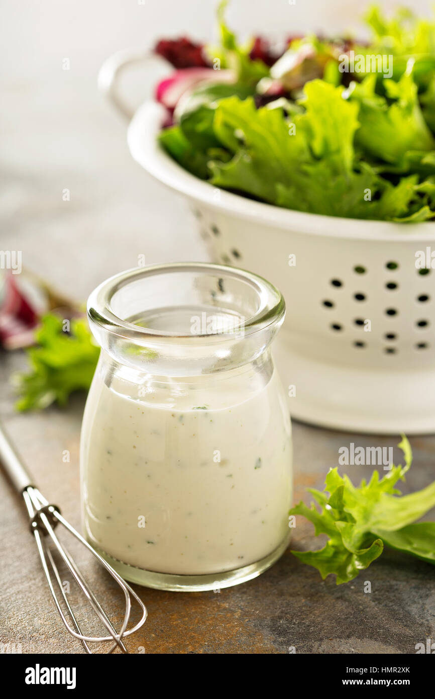 Homemade ranch dressing in a small jar with fresh greens Stock Photo