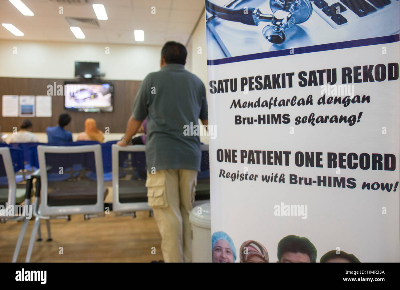 A patient is seen standing near a sign promoting the One Record system ...