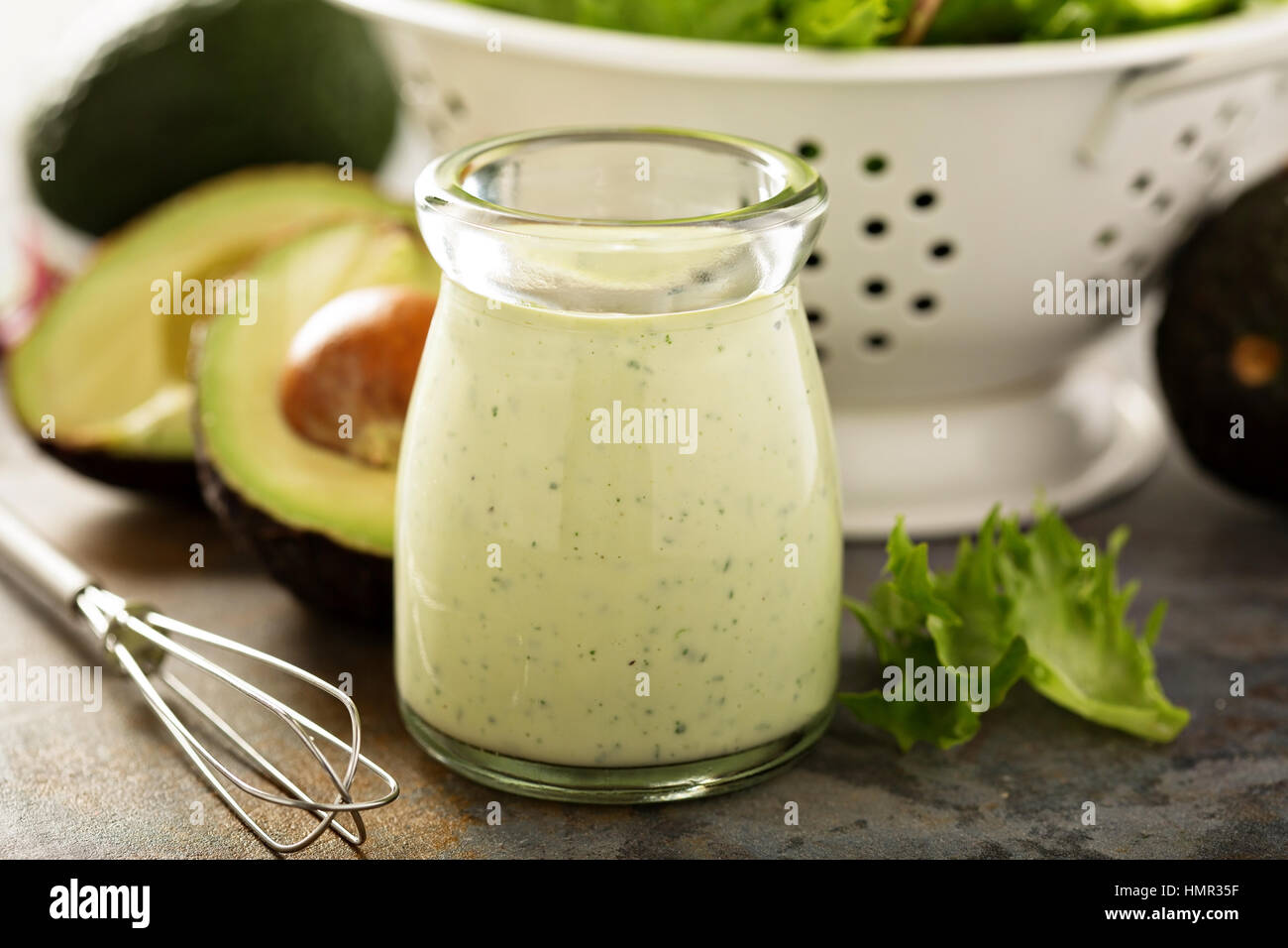 Homemade avocado ranch dressing in a small jar with fresh greens Stock