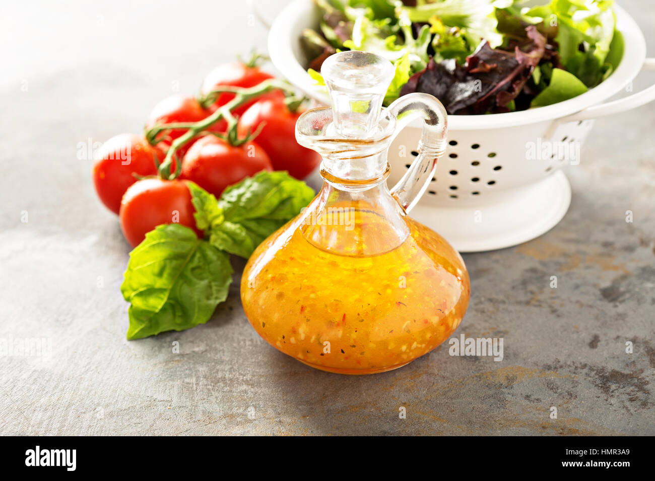 Italian vinaigrette dressing in a vintage bottle with fresh vegetables on the table Stock Photo