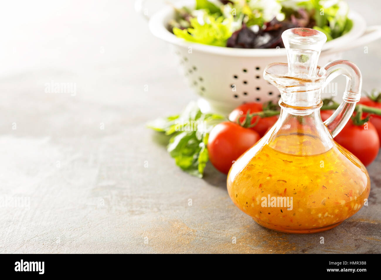 Italian vinaigrette dressing in a vintage bottle with fresh vegetables on the table Stock Photo