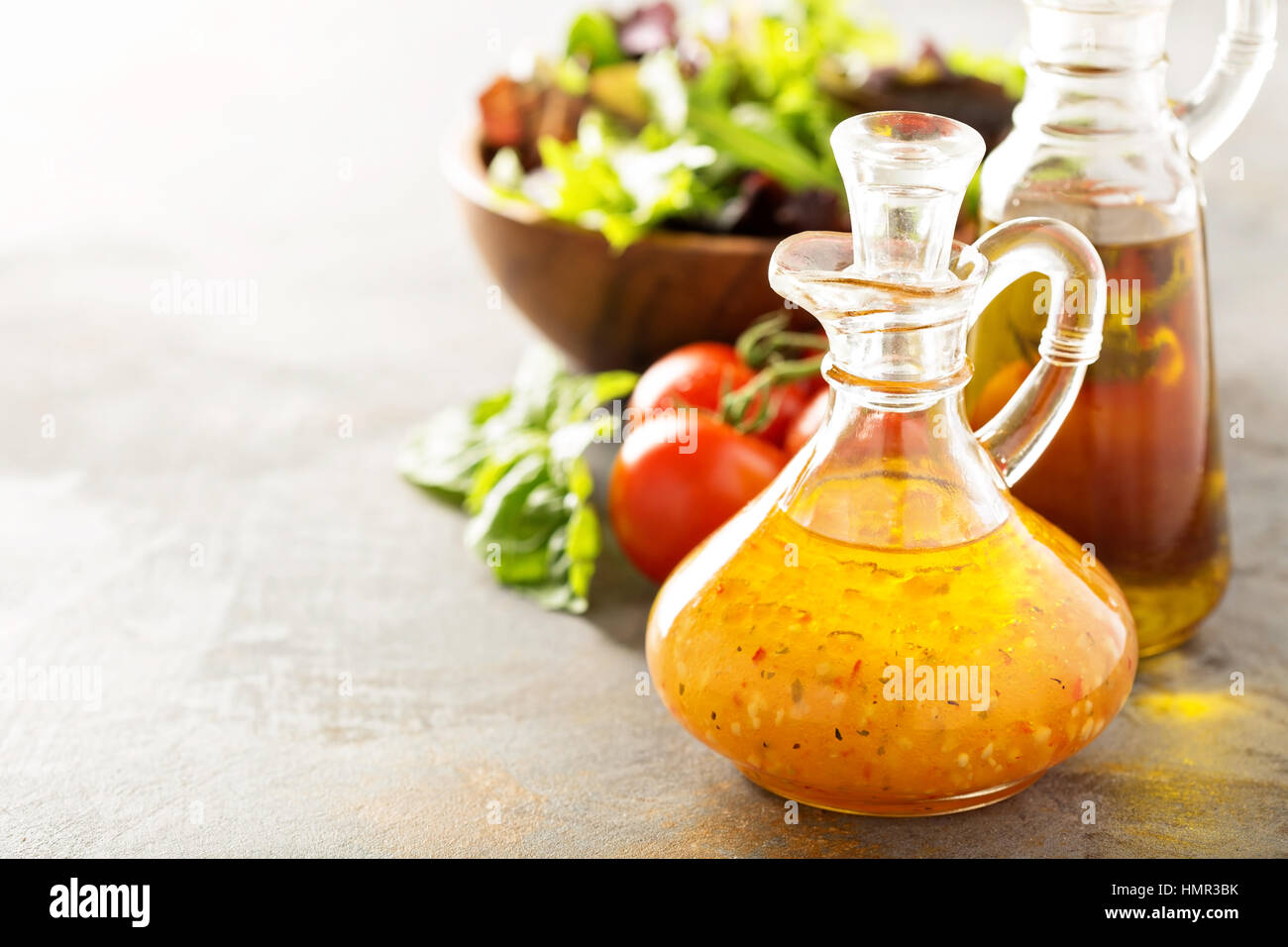 Italian vinaigrette dressing in a vintage bottle with fresh vegetables on the table Stock Photo
