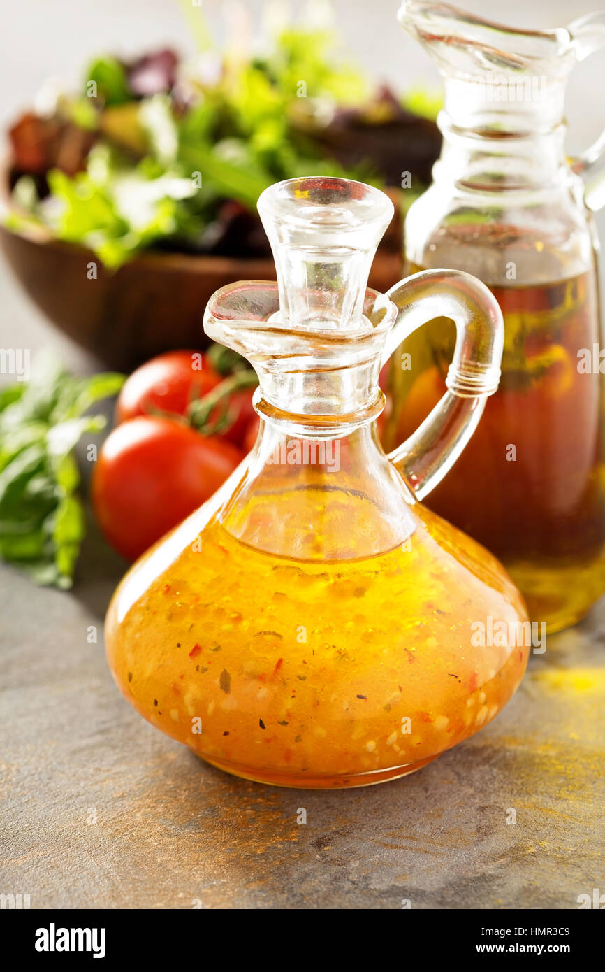 Italian vinaigrette dressing in a vintage bottle with fresh vegetables on the table Stock Photo