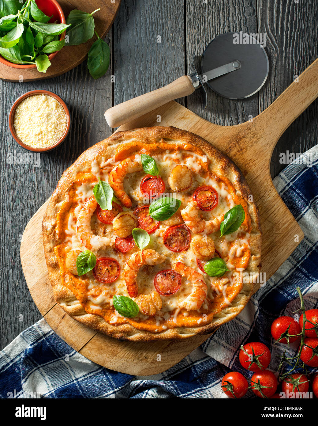 A delicious seafood pizza with shrimps, scallops, tomato, and basil with zesty red pepper sauce. Stock Photo