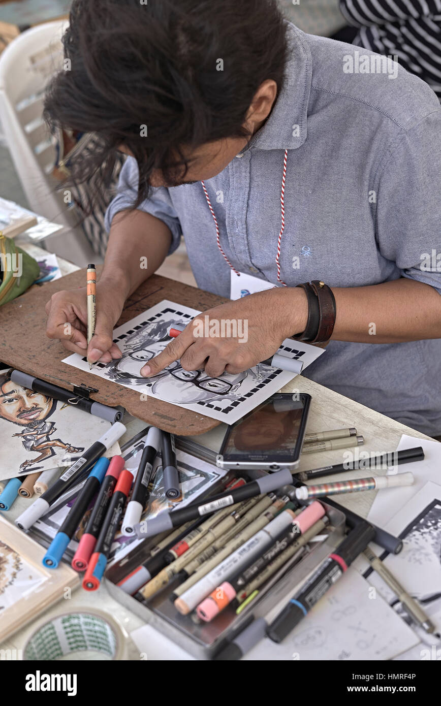 Artist drawing caricature of his subject. Pattaya Arts Festival 2017. Thailand S. E. Asia Stock Photo