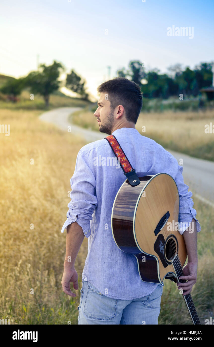 bearded man with a guitar in the field Stock Photo
