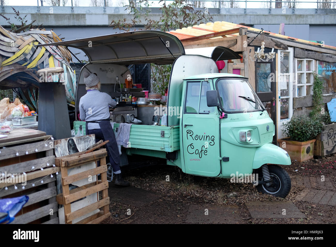 A woman serving food at 'The Roving Cafe' vintage three-wheeler car in The Nomadic Community Garden off Brick Lane in Shoreditch, East London, UK. Stock Photo