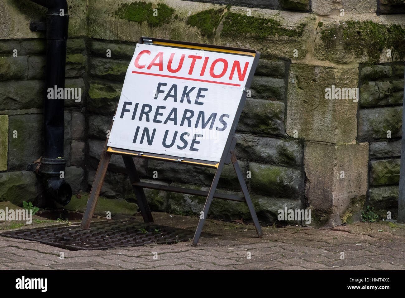 A sign warning people of fake firearm use during Doctor Who filming on Mount Stuart Square in Cardiff Bay, UK Stock Photo