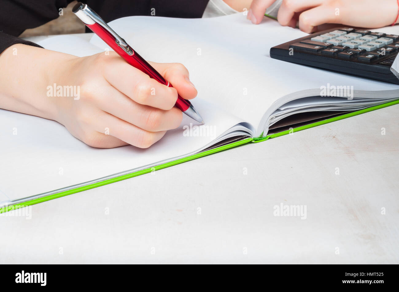 Woman calculating cost and writing a note in notebook Stock Photo