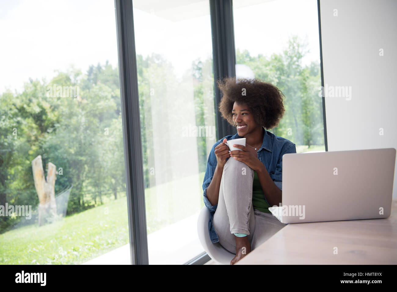 Young african american woman smiling sitting near bright window while ...