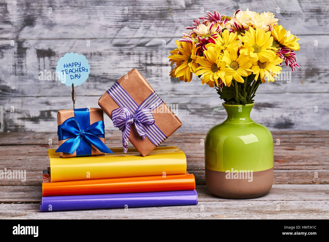 Books, flowers and gift boxes. Colourful books on wooden background. Stock Photo