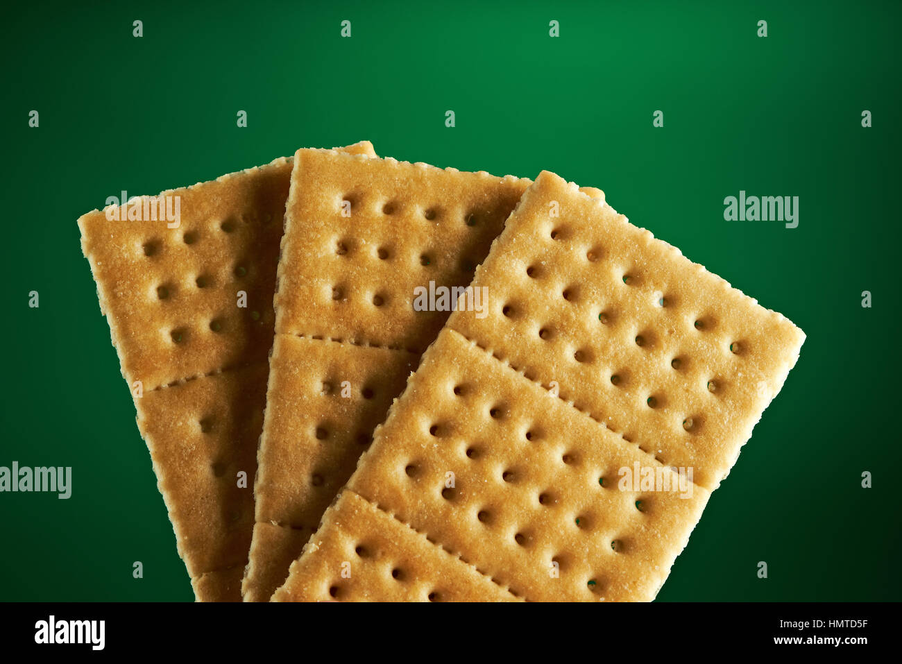 three gold fresh crackers isolated on green background Stock Photo