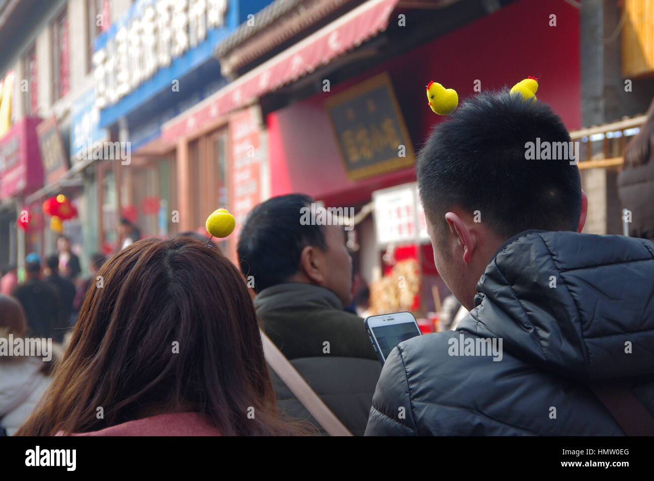 February 3, 2017 - Xi'An, Xi'an, China - Xi'an, CHINA-February 3 2017: (EDITORIAL USE ONLY. CHINA OUT) Tourists wearing little yellow chicken shaped decorations on head in Xi'an, capital of northwest China's Shaanxi Province, February 3rd, 2017. As the Year of the Rooster comes, little yellow chicken shaped decorations are becoming popular among tourists. Credit: SIPA Asia/ZUMA Wire/Alamy Live News Stock Photo