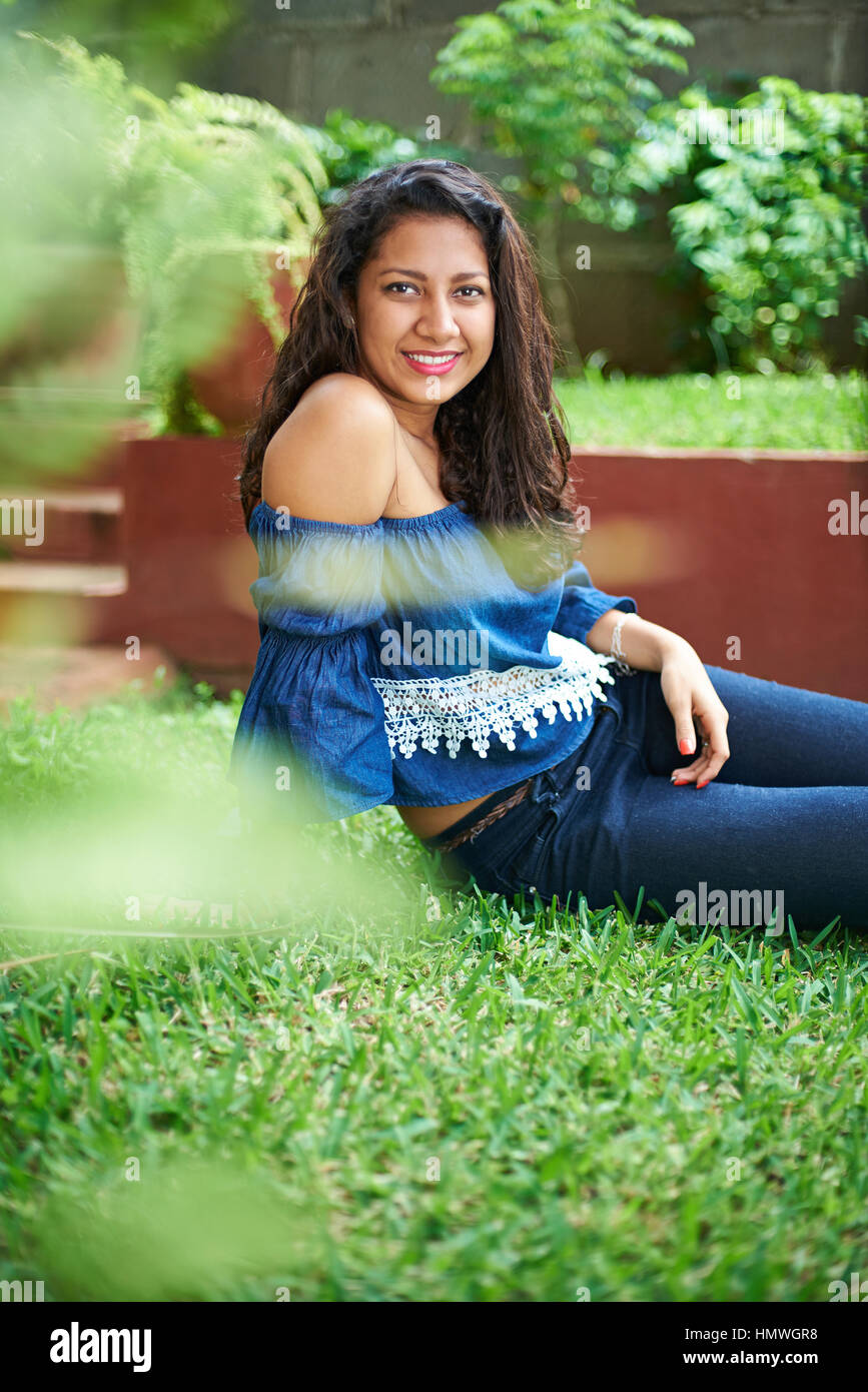 young hispanic woman sit in park green grass Stock Photo