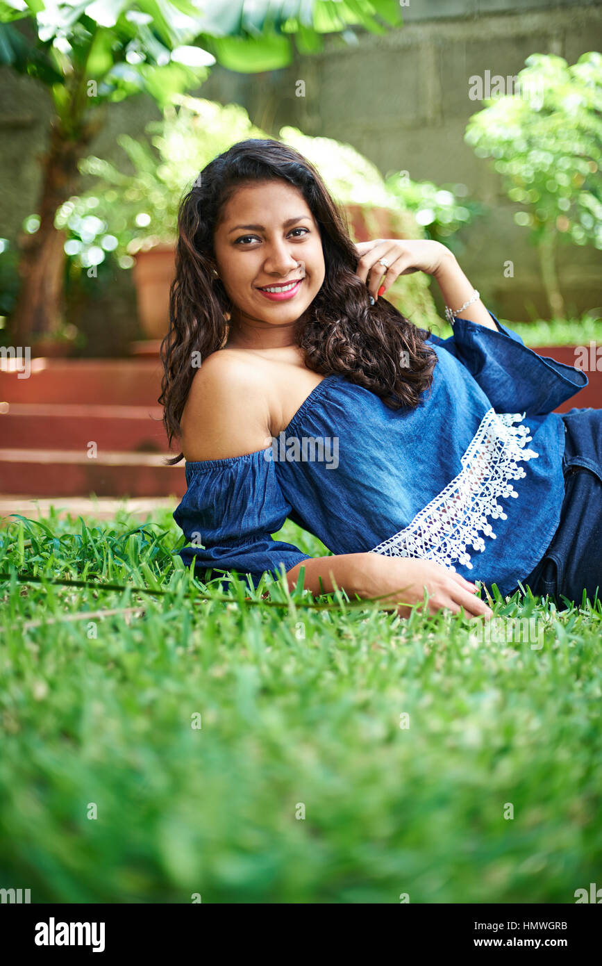 young latina girl laying on green grass Stock Photo