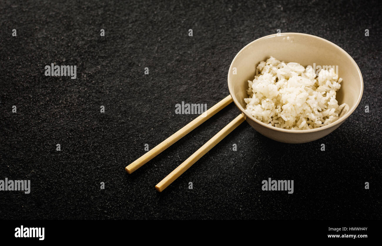 Asian rice in white bowl on dark background Stock Photo