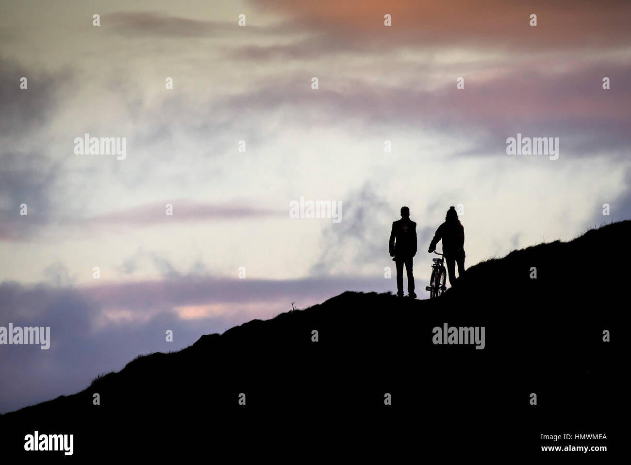 Two men seen in silhouette as they walk over Towan Headland in Newquay, Cornwall. Stock Photo
