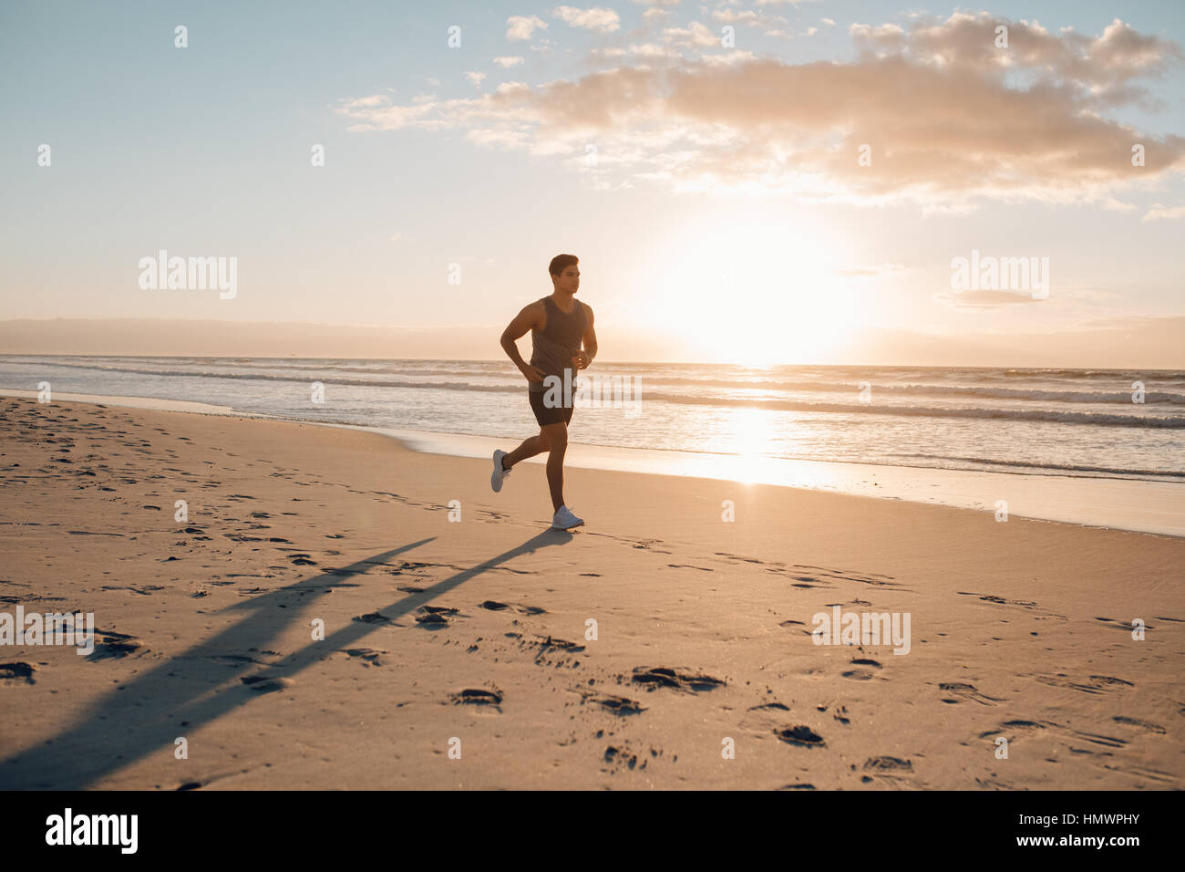 Young man training on the beach in morning. Young man on morning run outdoors. Stock Photo