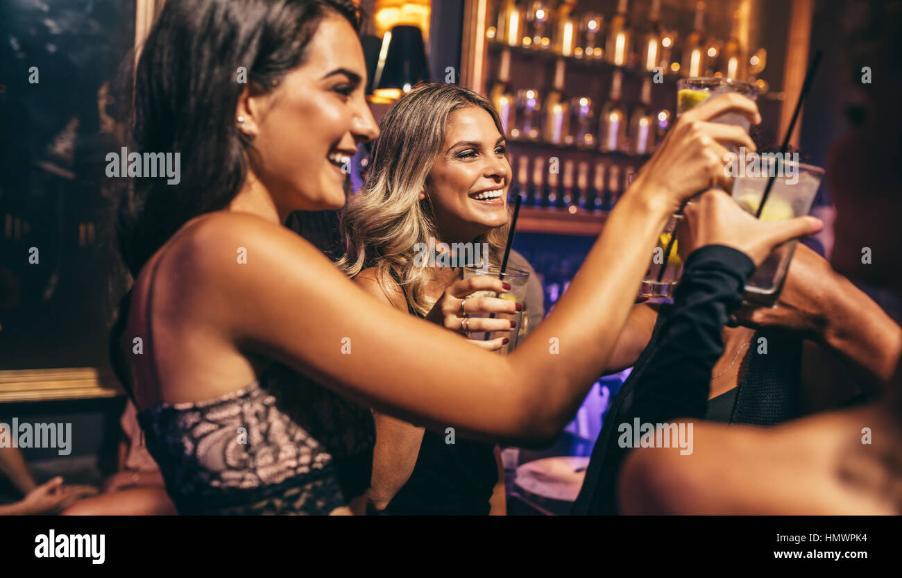 Group of young people celebrating at pub. Friends toasting cocktails in night club. Stock Photo