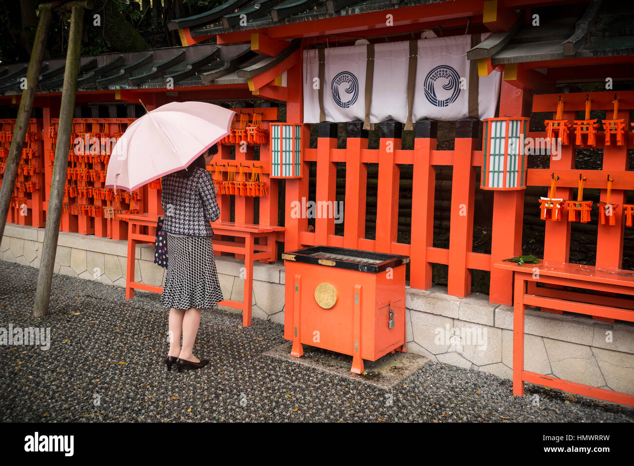 Young female praying, Fushimi Inari Taisha (Shinto shrine), Kyoto, Japan Stock Photo