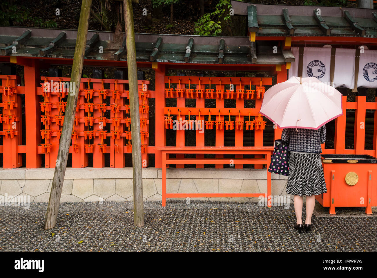 Young female praying, Fushimi Inari Taisha (Shinto shrine), Kyoto, Japan Stock Photo