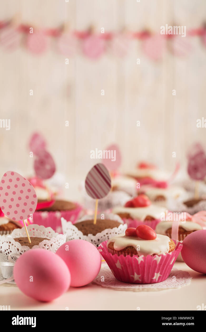 Easter cupcakes decorated with pink candy, paper eggs and ribbons. Selective focus. Stock Photo
