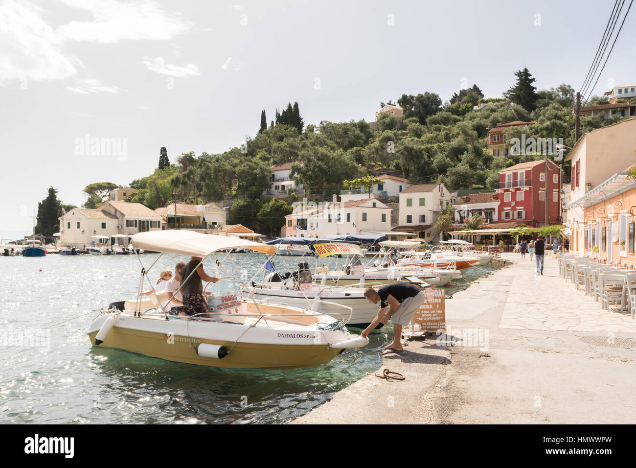 tourists mooring a hire boat at the tiny picturesque fishing village of Loggos, Paxos, Ionian Islands, Greece Stock Photo