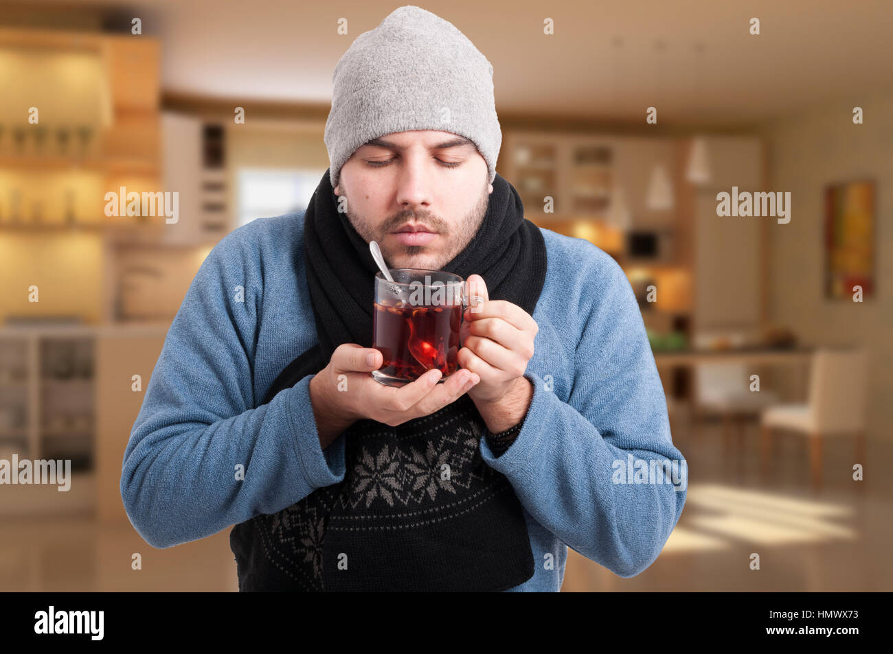 Sick man with flu holding and enjoying a warm cup of tea at his home Stock Photo