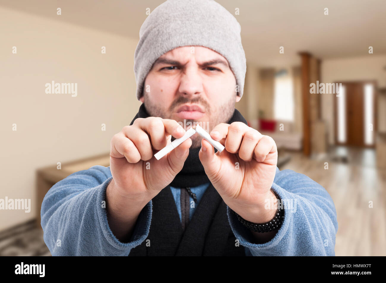 Sick man trying to quit smoking by breaking a cigarette in two as