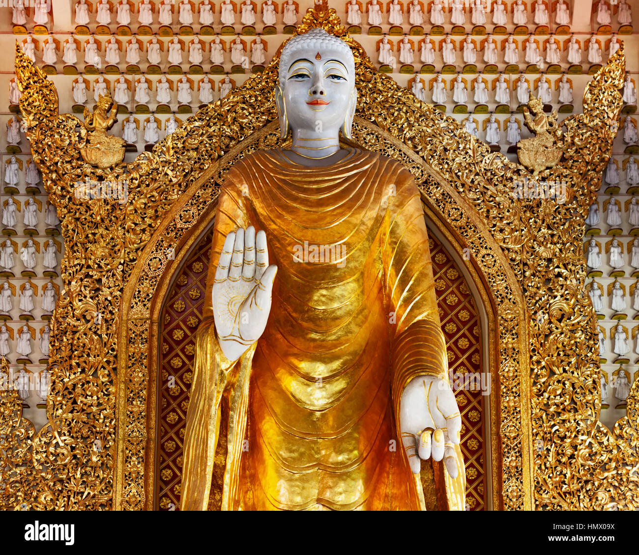 Huge gold statue of standing Buddha on 1000 Buddha wall background. Interior of ancient Burmese buddhist temple Dhammikarama in Georgetown on Penang Stock Photo